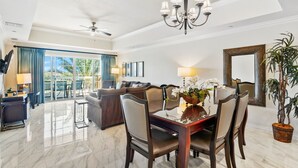 A spacious living room with a dining area, a ceiling fan, and a large window with a view of the outdoors.