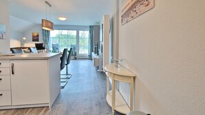 A modern kitchen with a dining area, a large window, and a view of the outdoors. - Seesternresidenz Appartement 21 - Seesternresidenz (Scharbeutz)