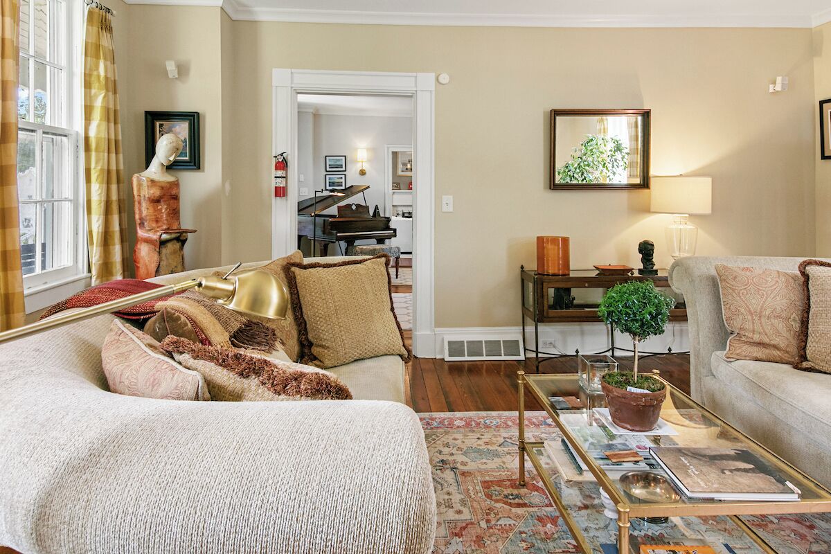 A cozy living room with a sofa, a coffee table, and a piano in the background.