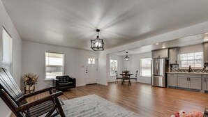 A spacious living room with a wooden floor, a rocking chair, and a dining area with a table and chairs. - Close to main attractions and Down Town Fort worth (River Oaks)