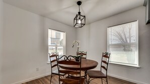 A dining area with a round wooden table and six chairs, a hanging light fixture, and two windows with blinds. - Close to main attractions and Down Town Fort worth (River Oaks)