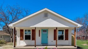 A small, single-story building with a white exterior, a blue door, and wooden shutters. - Close to main attractions and Down Town Fort worth (River Oaks)