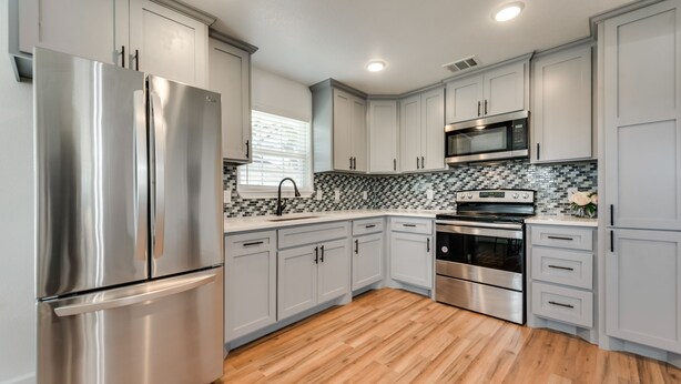 A modern kitchen with stainless steel appliances, light gray cabinets, and a patterned backsplash. - Close to main attractions and Down Town Fort worth (River Oaks)