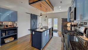 Una cocina moderna con armarios azules, una isla central y techo de madera.