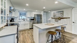 Una cocina moderna con armarios blancos, electrodomésticos de acero inoxidable y una isla de madera con taburetes.
