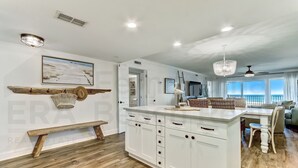 Una cocina moderna con armarios blancos, una banca de madera y un comedor con vistas.