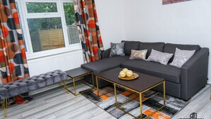 Una sala de estar moderna con un sofá seccional gris, un banco tapizado y una mesa de centro con bolas decorativas.