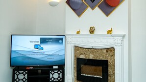Una sala de estar con televisor de pantalla plana, chimenea y decoración en la pared.