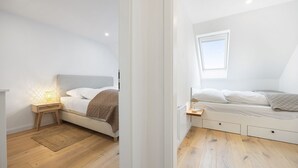 A modern bedroom with a bed, bedside tables, and a window.