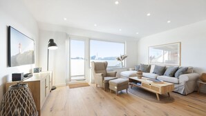 A modern living room with a sofa, armchairs, a coffee table, and a TV.