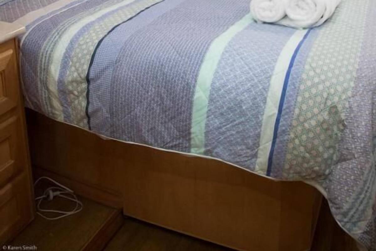 A bedroom with a bed, wooden headboard, and a window with curtains.