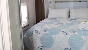 A bedroom with a bed, a window, and a ceiling vent. - Longford Riverside Caravan Park (Longford)