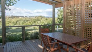 A wooden deck with a table and chairs, overlooking a grassy landscape. - Longford Riverside Caravan Park (Longford)
