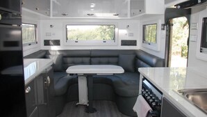 A compact RV interior with a kitchenette, a dining table, and seating area. - Longford Riverside Caravan Park (Longford)