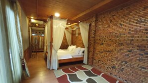 A room with a bed, a brick wall, and a wooden ceiling. - Kampung Turis Resort & Waterpark (Tegalwaru)