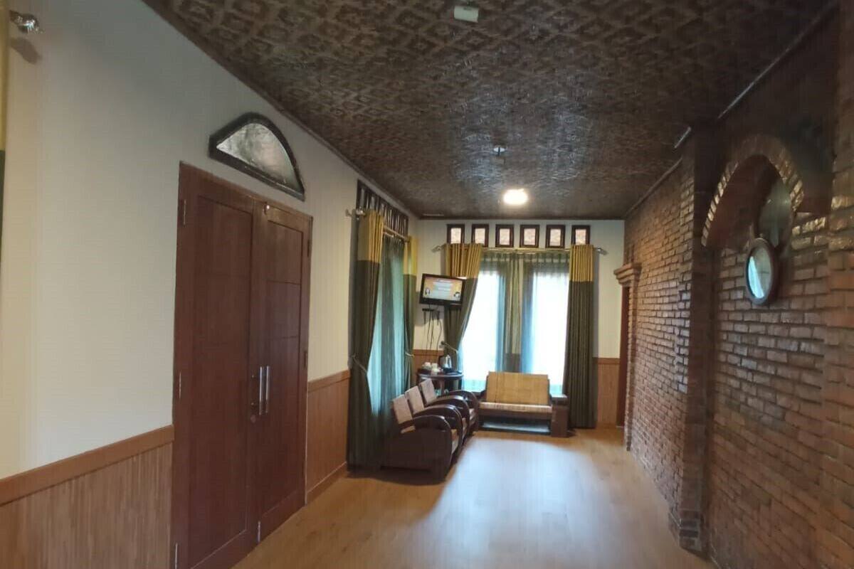 A hallway with a patterned ceiling, wooden flooring, a sofa, curtains, and a clock on the wall.