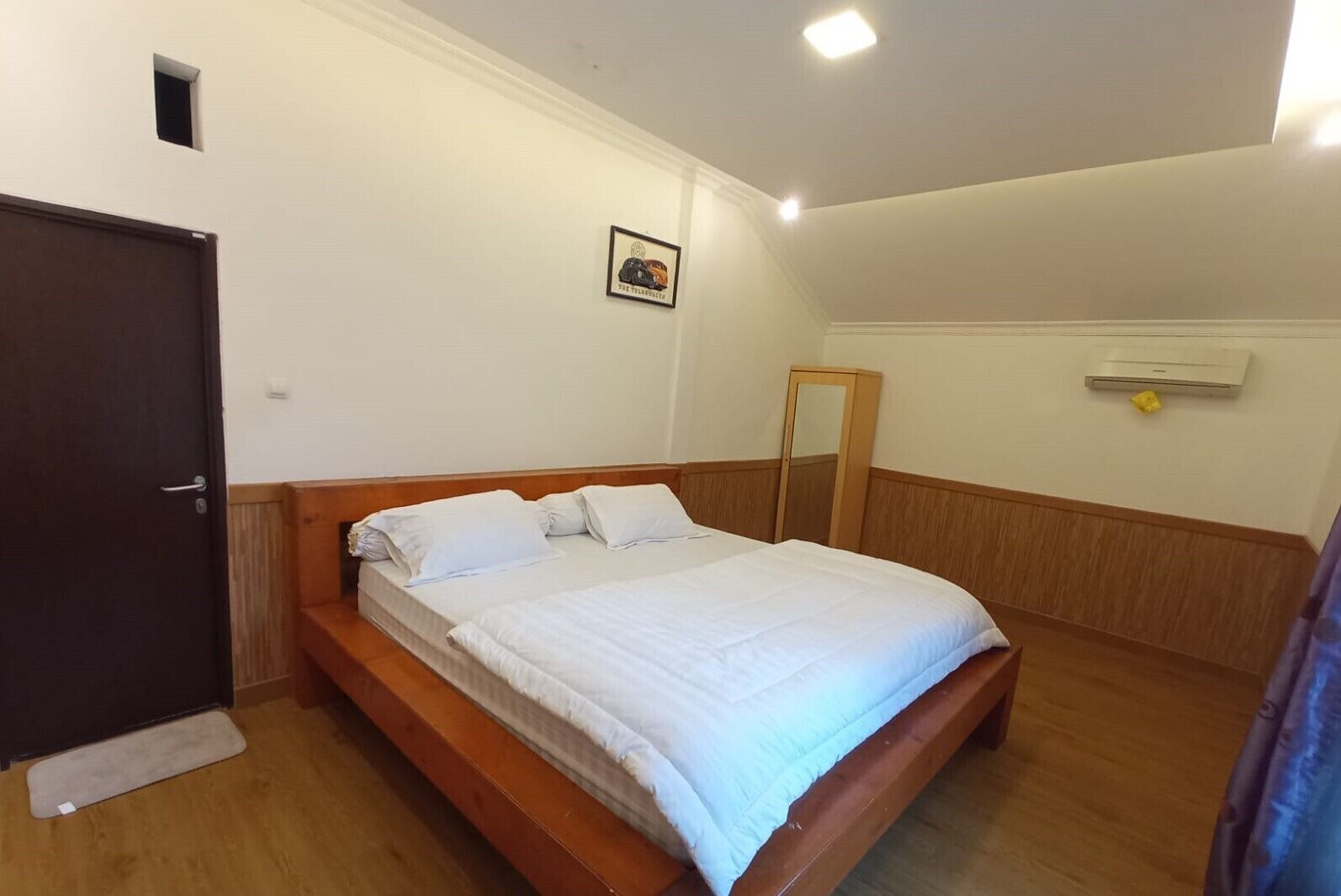 Ein Einzelbett mit weißer Bettwäsche in einem Zimmer mit Holzvertäfelung und einem kleinen Fenster.