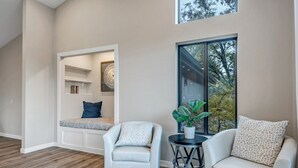 A modern living room with two white leather sofas, a small round table, and a built-in bench with shelves.