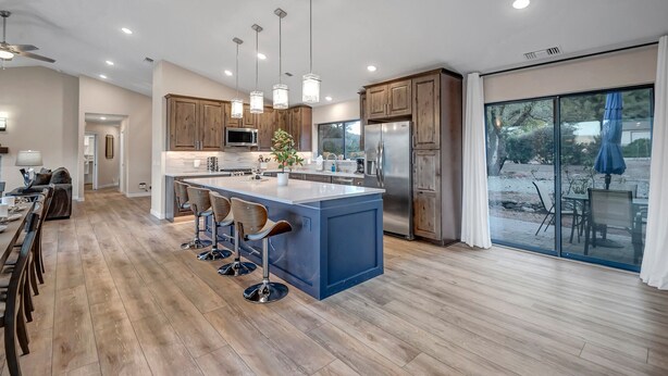 A modern kitchen with a large island, wooden cabinets, and stainless steel appliances.
