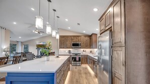 A modern kitchen with wooden cabinets, stainless steel appliances, and a large island.