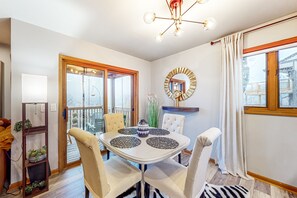 Uma sala de jantar com uma mesa branca, cadeiras bege e um candelabro.