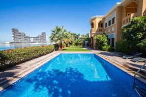 A swimming pool with a view of a modern building and palm trees.