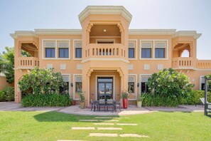 A large, two-story building with a symmetrical facade, multiple balconies, and a central entrance with a glass door.