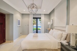 Un dormitorio con una cama grande, una mesita de noche, una lámpara y vistas al exterior.