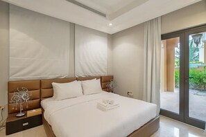 A modern bedroom with a large bed, a nightstand, and a view of the outdoors through a glass door.