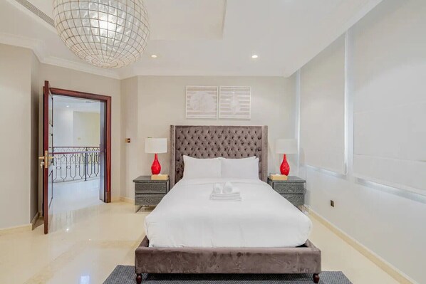 Habitación de hotel con una cama grande, dos mesitas de noche, un candelabro y una puerta que da a un balcón.