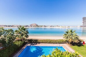 A pool with a view of a beach and a resort in the background.