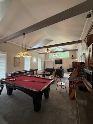 A pool table in a room with a ceiling fan, a television, and a mural. - Indoor Pool + Hot Tub + Fire Pit + Game Room (Sevierville)