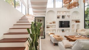 A modern interior with a staircase, a living area with a sofa, a coffee table, and a TV.