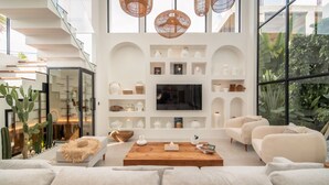 A modern living room with a large TV, white shelves, and a wooden coffee table.