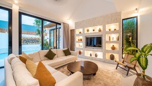 A modern living room with a sofa, coffee table, and shelves with decorative items.