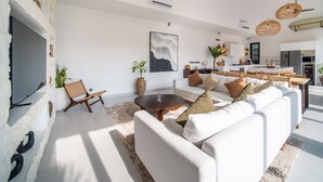 A modern living room with a white sofa, a round coffee table, and a stone accent wall.