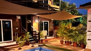 A two-story wooden house with a swimming pool, potted plants, and outdoor furniture. - The Emerald Morjim (Morjim)