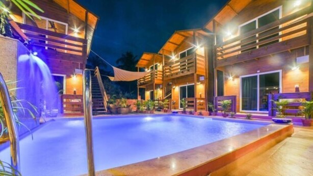 A pool area with wooden buildings and outdoor lighting. - The Emerald Morjim (Morjim)