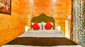 A wooden cabin room with a bed, a headboard, and a painting on the wall. - The Emerald Morjim (Morjim)