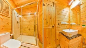 A wooden cabin bathroom with a glass-enclosed shower, a white toilet, and a wooden vanity with a sink. - The Emerald Morjim (Morjim)
