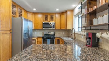 Full kitchen with a stainless fridge and granite counters