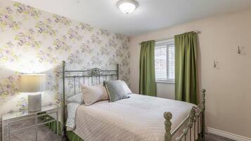 Bedroom with a floral accent wall and green curtains