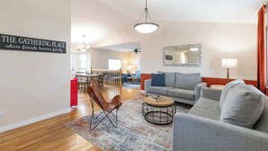 A living room with a sofa, armchair, coffee table, and a dining area with a table and chairs. - Spacious Family Home • Game Room • Pets Welcome (Orem)