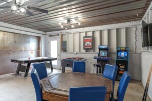 Um quarto com mesa de pebolim, mesa de tênis de mesa e jogos de fliperama.