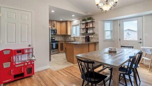 A kitchen with wooden cabinets, a red toy stove, a dining table with chairs, and a chandelier. - Spacious Family Home • Game Room • Pets Welcome (Orem)