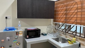 A compact kitchen with a microwave, sink, and a small refrigerator. - Bukit Tinggi Homestay (Klang)