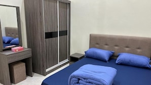 A neatly made bed with blue bedding, a wooden wardrobe with a mirror, and a small bedside table with a lamp. - Bukit Tinggi Homestay (Klang)