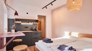 A modern hotel room with a bed, a desk, a chair, and a kitchenette. - Guest House 'Alte Seifensiederei - Malala' with Shared Terrace, Shared Garden and Wi-Fi (Bad Tölz)