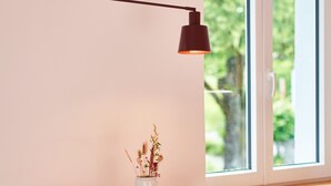 A pink desk with a white vase, two stools, a wall-mounted lamp, and a window with a view of greenery. - Guest House 'Alte Seifensiederei - Malala' with Shared Terrace, Shared Garden and Wi-Fi (Bad Tölz)