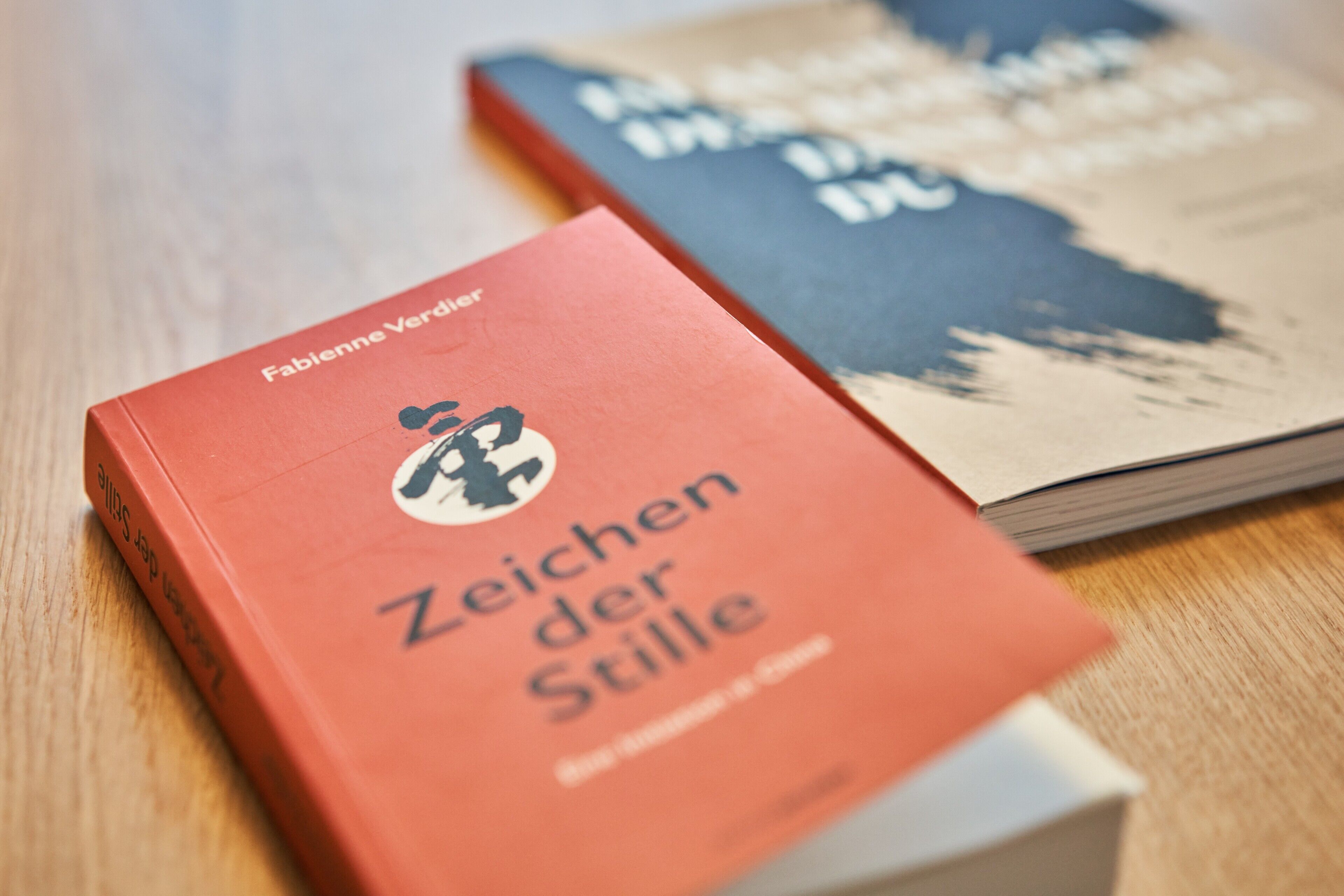 Zwei Bücher auf einer Holztischplatte.